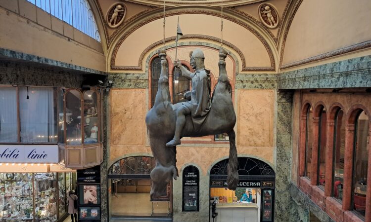 David Černý's St. Wenceslas sculpture of a figure sitting on an upside down dead horse hanging from the ceiling of a public building in Prague